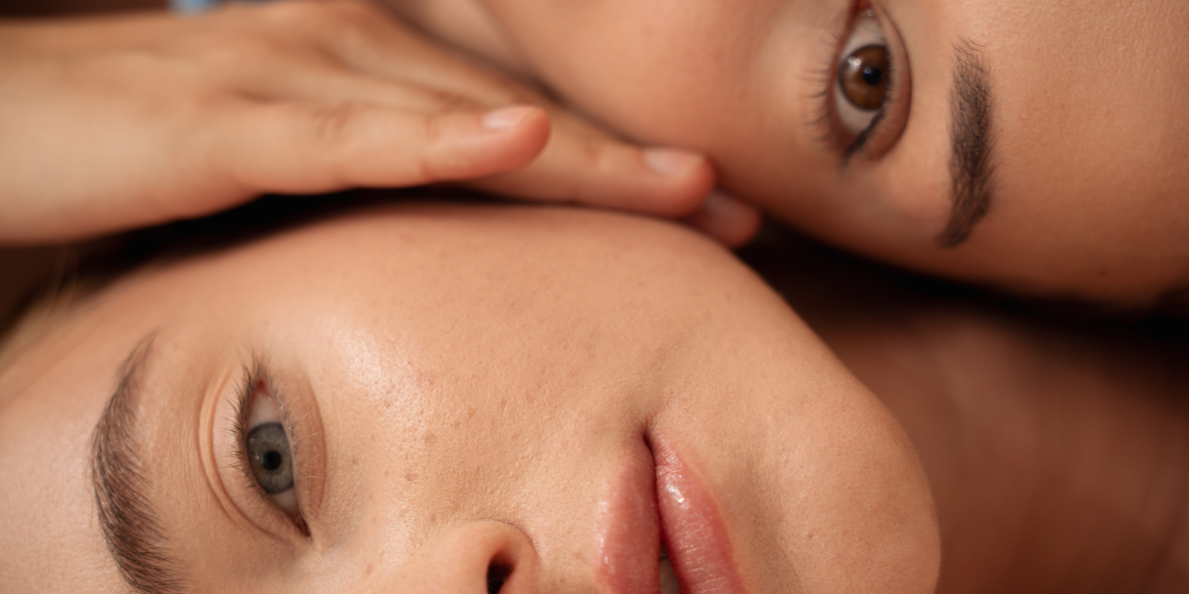 Close-up of two people with one resting their head on the other's shoulder.